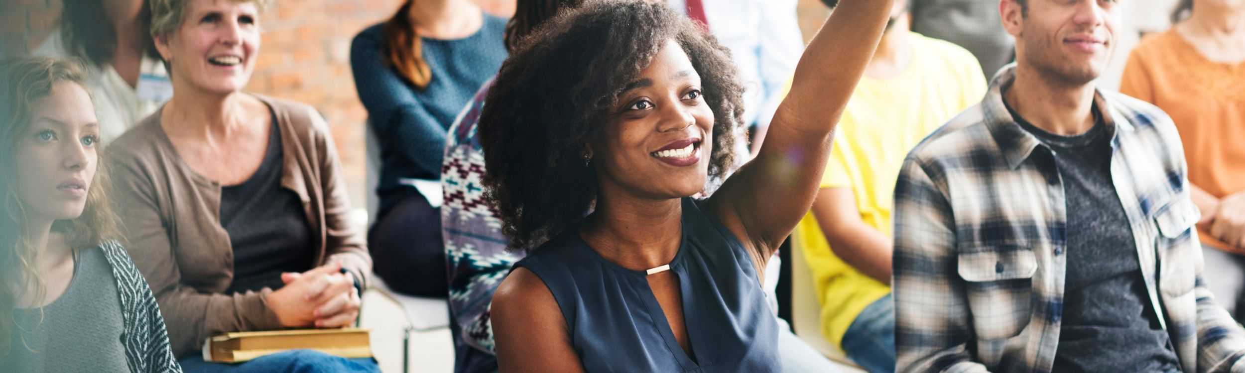 a woman raising her hand to provide review acquisition strategies for her brand